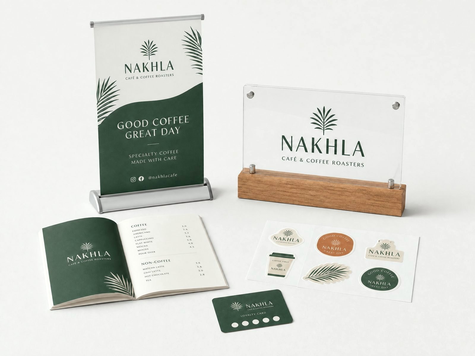 Cafe branding and signage: a countertop pull-up banner, an acrylic table sign on a wood base, a printed menu, a sticker sheet and a loyalty card
